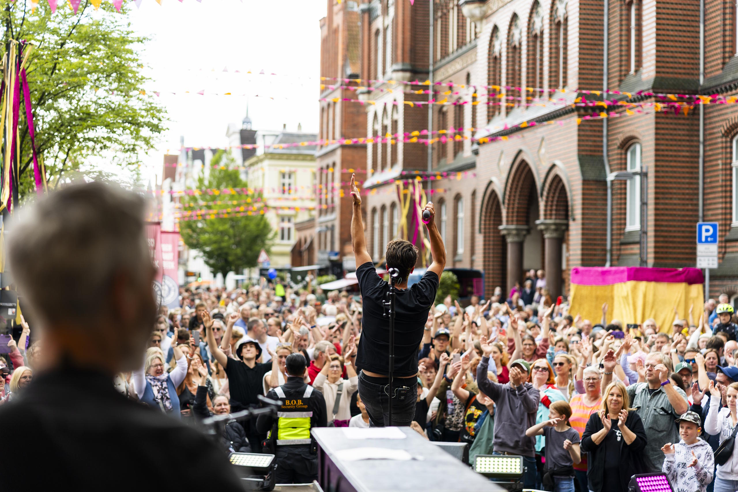 Konzertpublikum feiert vor einer Bühne in der Lübecker Altstadt beim HanseKulturFestival.