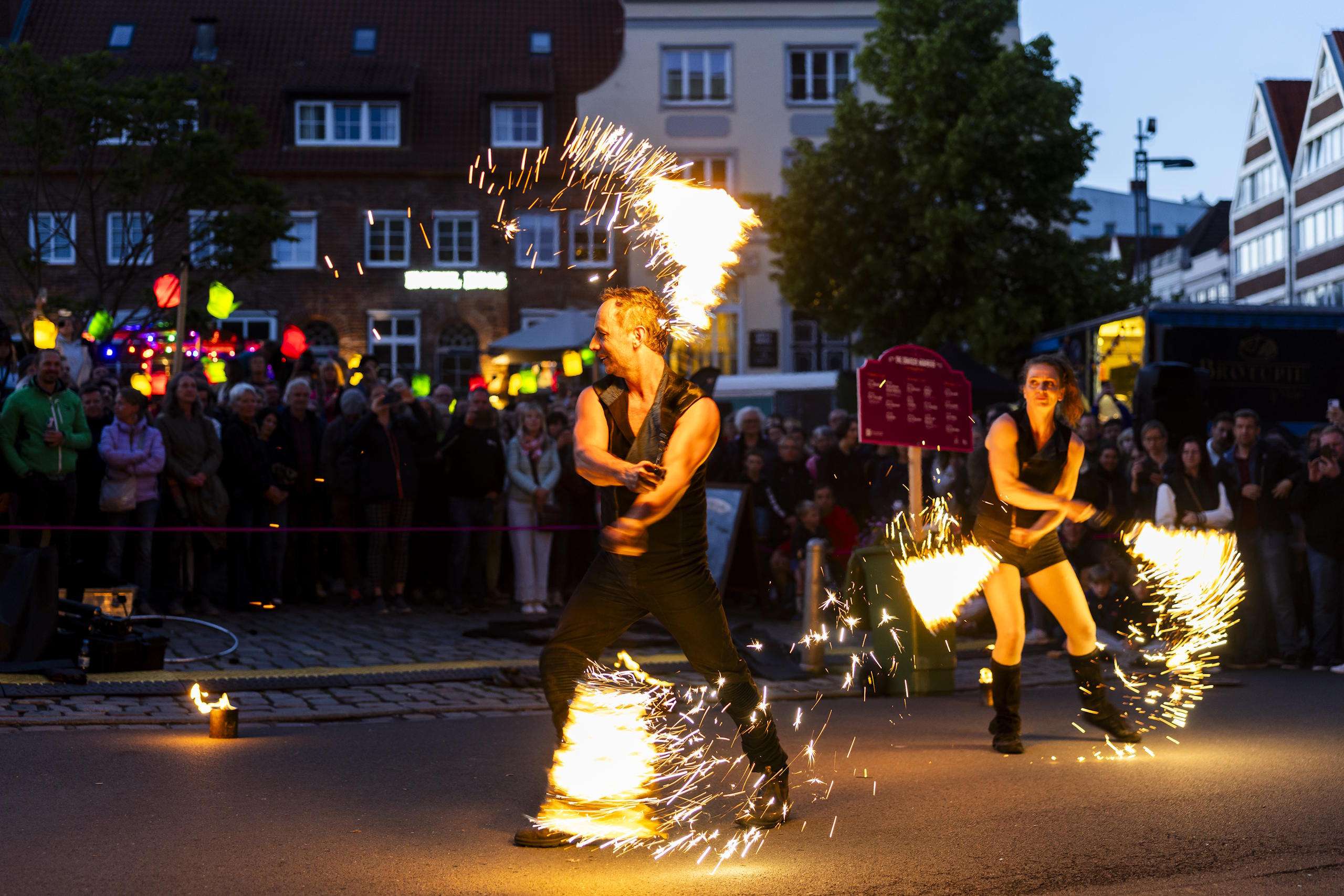 Feuershow mit Funkenflug vor Publikum in der Lübecker Altstadt am Abend des HanseKulturFestivals.