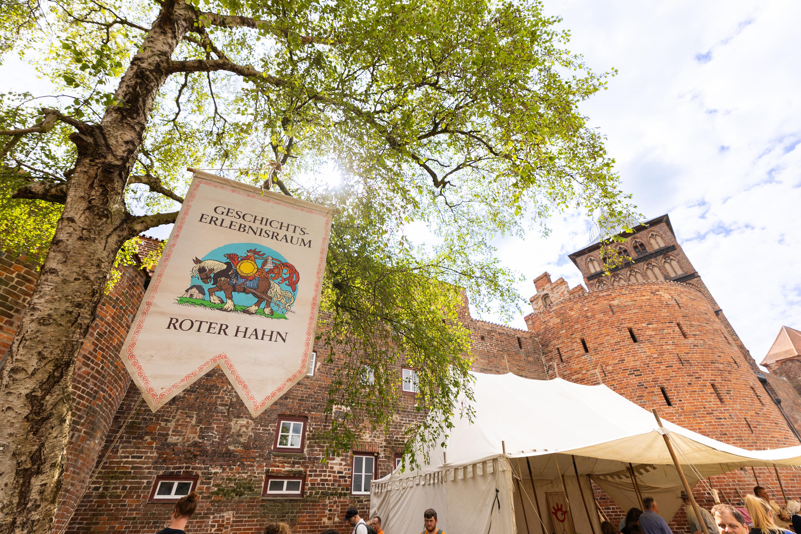 Mittelalterliches Lager am Geschichtserlebnisraum Roter Hahn vor historischen Backsteinmauern in Lübeck.