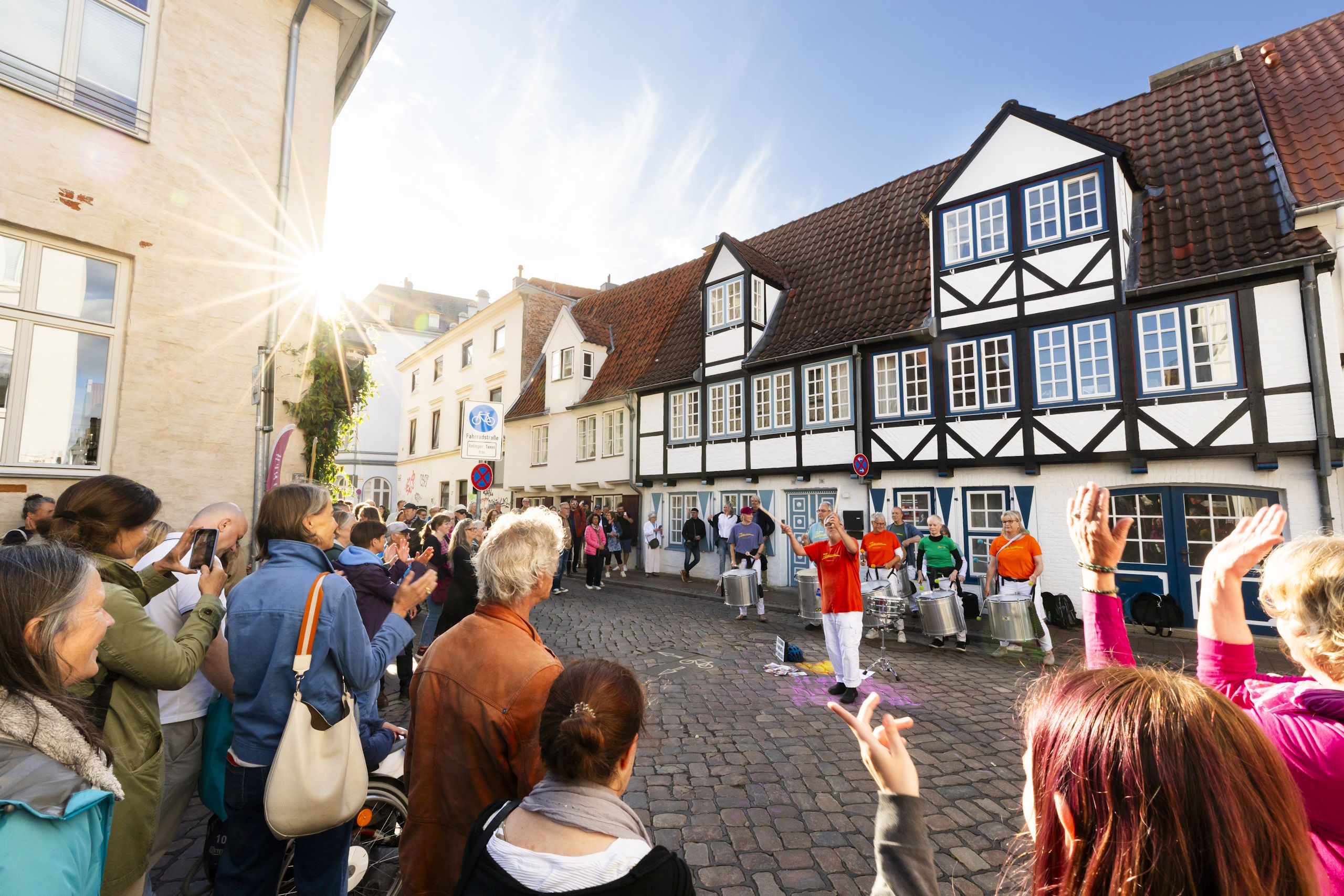 Straßenmusik und Trommelperformance vor historischen Fachwerkhäusern in der Lübecker Altstadt.