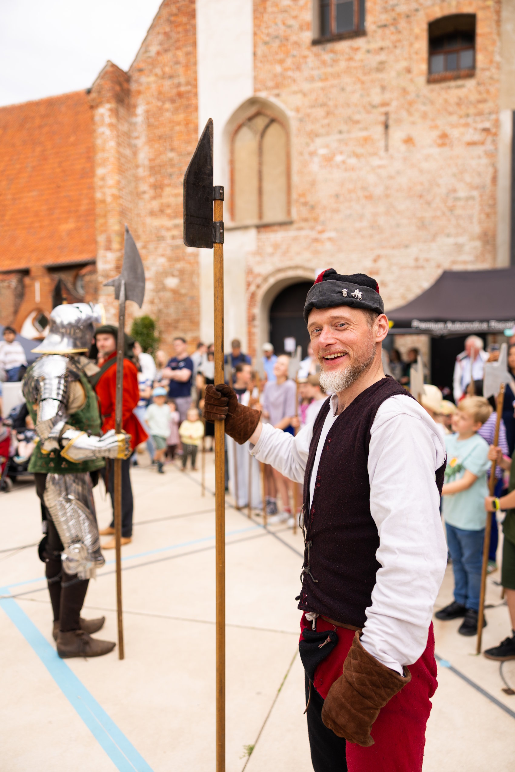 Mittelalterdarsteller mit Hellebarde vor historischem Gebäude beim HanseKulturFestival in Lübeck.