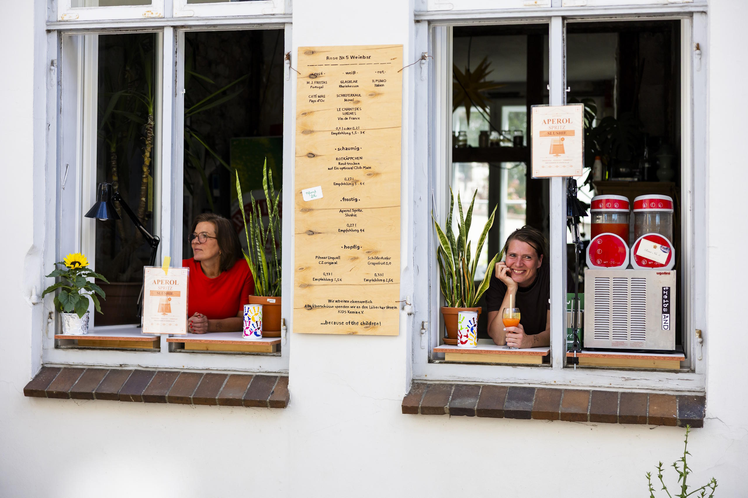 Zwei Frauen bieten Getränke aus den Fenstern eines Altstadthauses während des HanseKulturFestivals an.