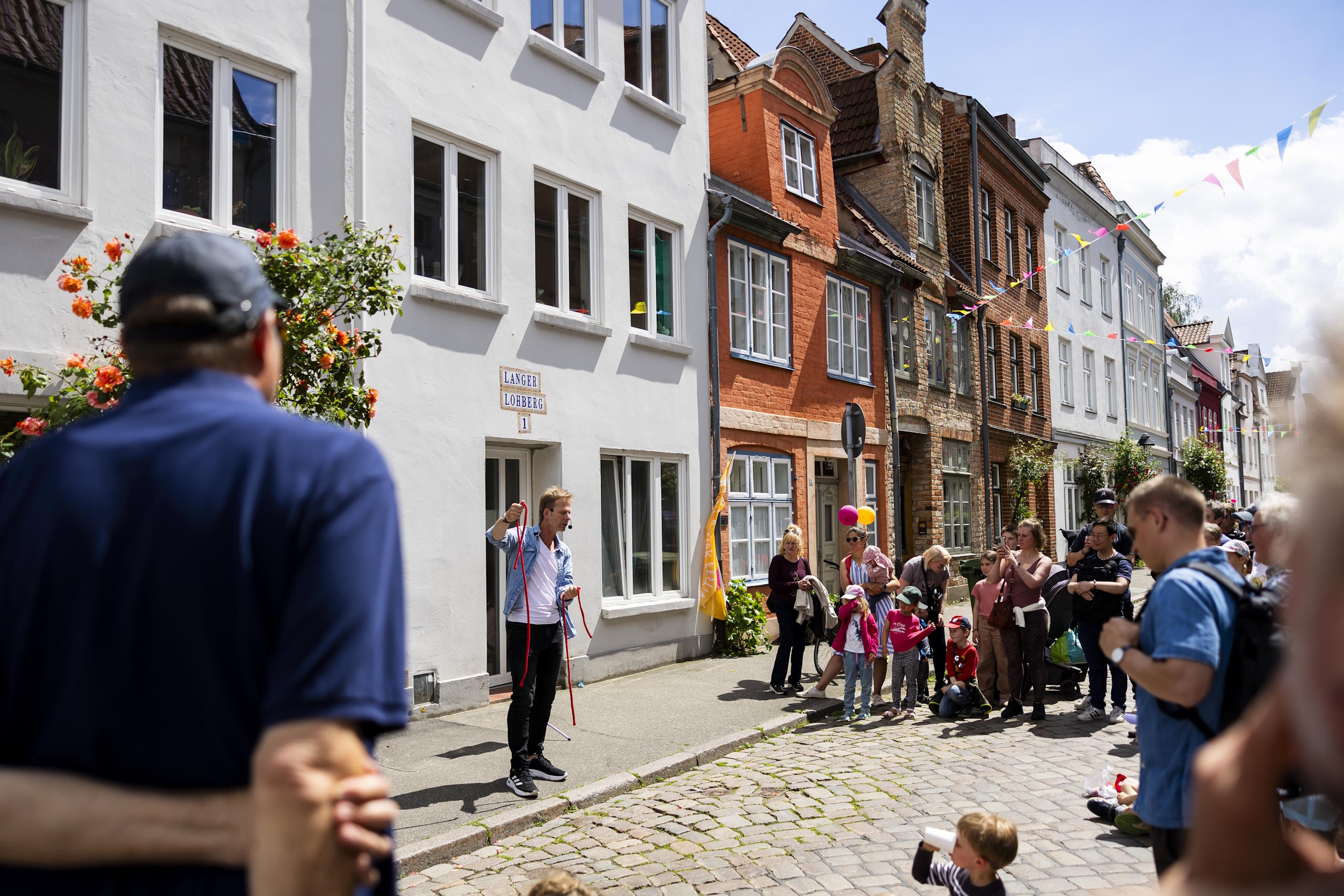 Straßenkünstler begeistert Publikum in einer geschmückten Gasse der Lübecker Altstadt.