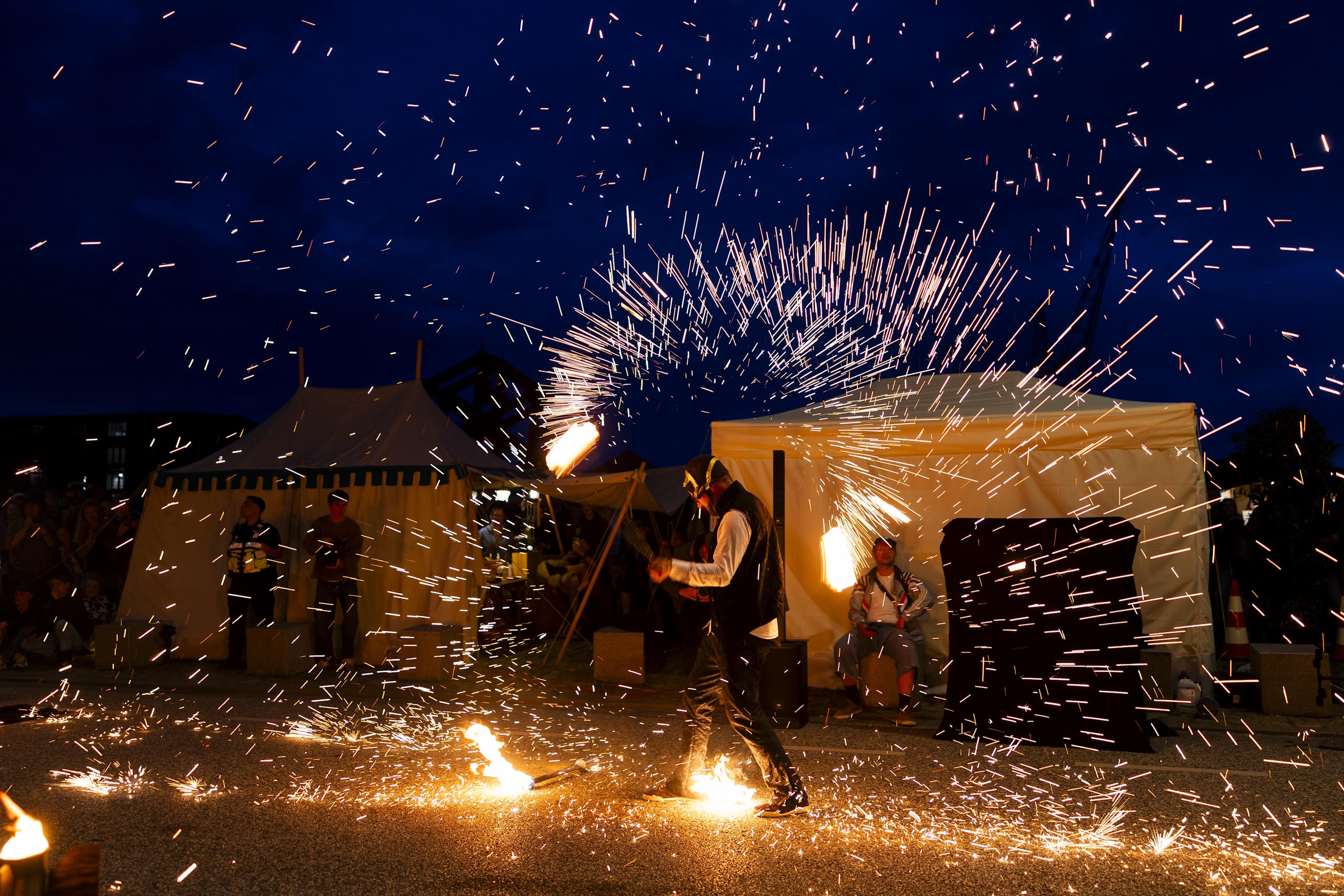 Feuershow mit Funkenregen vor historischem Lager und Publikum am Abend des HanseKulturFestivals.